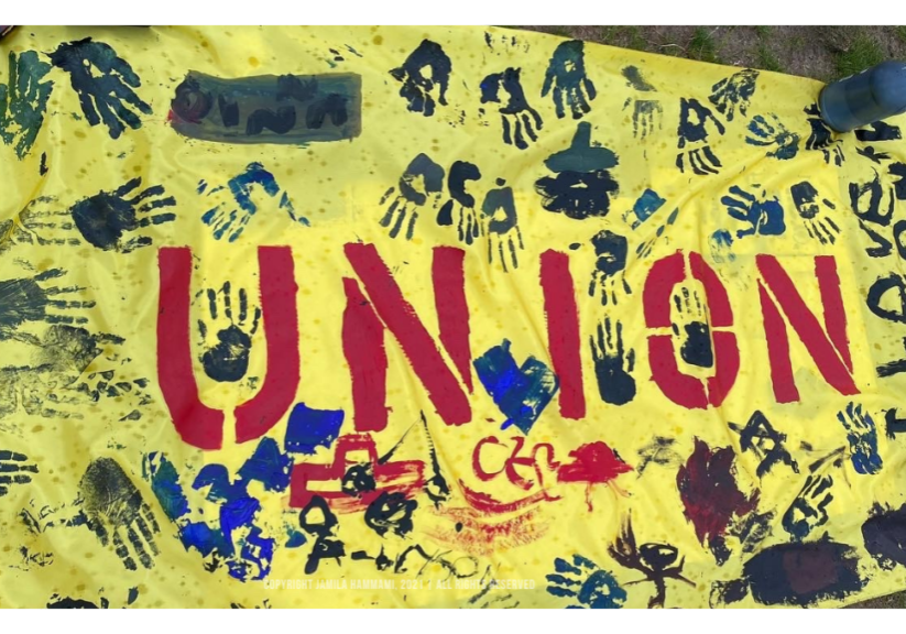 ALU Union Drive _I love Union_ Finger painted banner with ALU children _ _ Image Credit_ Copyright Jamila Hammami, 2021 _ All Rights Reserved Finger-painted “Union” banner by Amazon Labor Union (ALU) workers’ children, outside of Amazon’s Staten Island JFK8 fulfillment center, New York, July 2021 | Photo Credit & Copyright: Jamila Hammami, 2021. | All Rights Reserved.